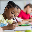 Image of young students writing at desk, doing school work.