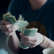 Image of young woman counting dollar bills.