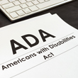 Photo of stack of papers next to keyboard that says ADA Americans with Disabilities Act