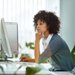 Image of woman working on computer, hand on mouse leaning forward with other hand under chin.