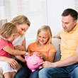 Parents with two daughters and piggy bank.