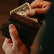 Image of man pulling dollar bills out of his wallet.